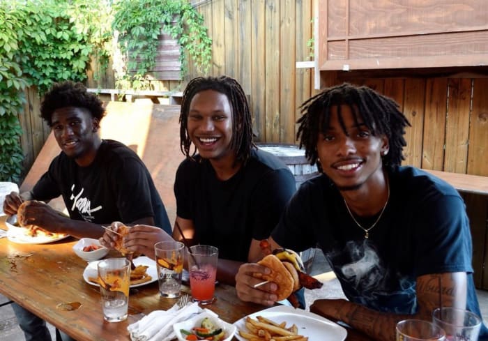 Indiana basketball sophomores Kaleb Banks (left), Malik Reneau (middle) and CJ Gunn (right) try the "Malik Reneau Burger" at Big Woods restaurant in Bloomington, Ind.